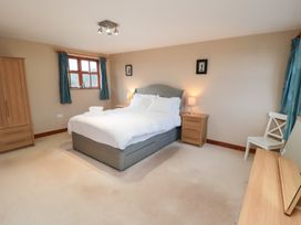 A bedroom with a bed, nightstand, lamp, and window at Pasture View in Sneatonthorpe near Whitby