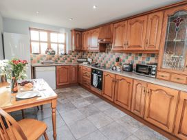 A kitchen with wooden cabinets and a dining table at Beck View in Whitby