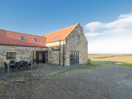 A stone building with a dining area outside at Wheelhouse Cottage in 