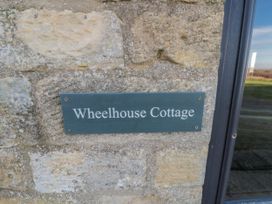 A sign displaying Wheelhouse Cottage on a stone wall at Wheelhouse Cottage