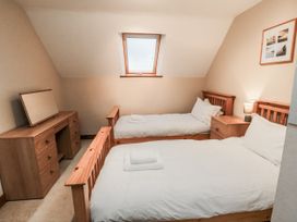 A bedroom with two single beds and a desk at Wheelhouse Cottage in Sneatonthorpe near Whitby