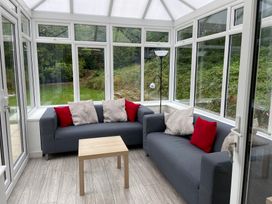 A conservatory with sofas and a coffee table at Hafod Y Graig in Morfa Bychan