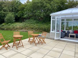 A conservatory with seating and tables overlooking the garden at Hafod Y Graig in Morfa Bychan