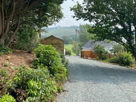 A gravel driveway leading to a wooden shed and house at Hafod Y Graig in Morfa Bychan