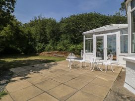 A garden with a table and chairs near a conservatory at Seaview Hafod Y Graig Morfa Bychan