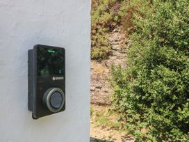 An electric vehicle charger mounted on a wall with surrounding plants at Seaview Hafod Y Graig Morfa Bychan