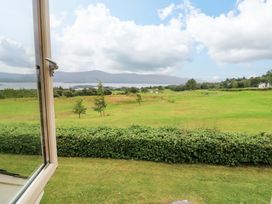 A view of a grassy area with trees and a lake at 25 Ring of Kerry Holiday Cottages in Kenmare
