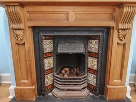 A fireplace with pinecones in the hearth at Glen Avon Seahouses