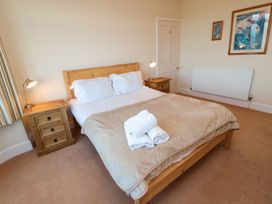 A bedroom with a wooden bed and bedside table at Glen Avon in Seahouses