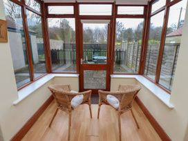 A conservatory with two chairs and a door leading to the garden at Glen Avon in Seahouses