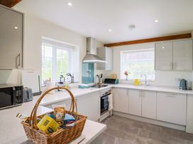 A kitchen with appliances and a basket of food items at The Cottage Middle Westwater
