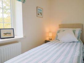 A bedroom with a bed, lamp, and paintings at The Cottage Middle Westwater in Westwater Nr Axminster