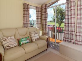 A living room with a sofa and curtains at Cody Cottage Lodge near Mullacott Park near Ilfracombe