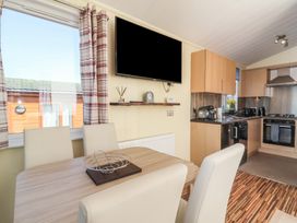 A kitchen with table and chairs at Cody Cottage Lodge in Mullacott Park near Ilfracombe