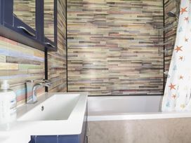 A bathroom with a sink, mirror, and bathtub at Cody Cottage Lodge, Mullacott Park near Ilfracombe
