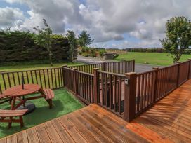 An outdoor seating area with a wooden table in the garden at Cody Cottage Lodge Mullacott Park near Ilfracombe