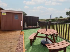 A garden with a table and shed at Cody Cottage Lodge Mullacott Park near Ilfracombe
