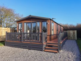 A wooden lodge with a deck and steps at Meadows Park 1 Great Hatfield near Hornsea