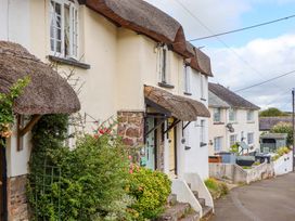 A view of a building with a thatched roof and garden at Cosy Nook South Molton