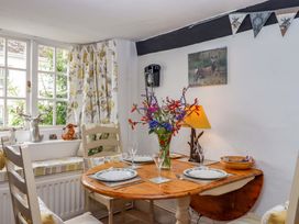 A dining room with a wooden table and floral curtains at Cosy Nook in South Molton