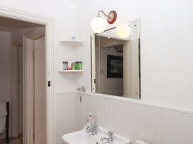 A bathroom with a sink, mirror and light at Cosy Nook in South Molton