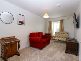 A living room with a red sofa and floral armchair at Cae Gwyn, Ty Croes