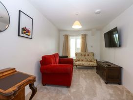 A living room with a red sofa, floral chair, and television at Cae Gwyn in Ty Croes