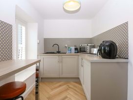 A kitchen with sink, toaster, microwave, air fryer, and bar counter at Cae Gwyn Ty Croes