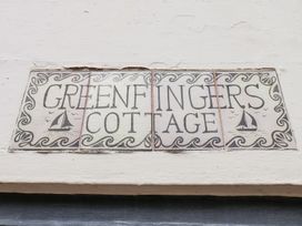 A sign that reads 'GREENFINGERS COTTAGE' on a wall at Greenfingers in Whitby