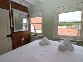 A bedroom with a bed and windows at Greenfingers in Whitby