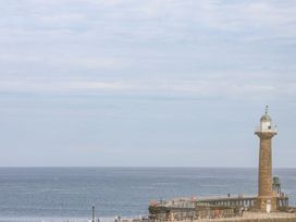 A lighthouse on a pier beside the ocean at Greenfingers in Whitby