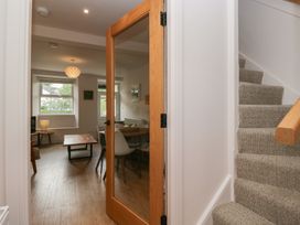 A hallway with a staircase and a door leading to a living area at Wansfell Nook in Ambleside