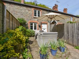 A garden with a couch and umbrella at Woodedge in Minehead