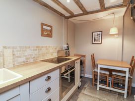 A kitchen with a countertop, stove, oven, and table at Woodedge in Porlock
