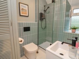 A bathroom with a toilet, shower, sink and a window at Woodedge in Porlock