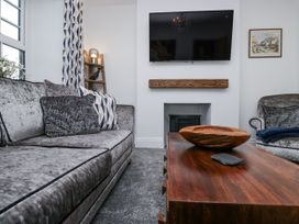 A living room with a sofa, armchair, and coffee table at Holy Trinity Cottage in Millom
