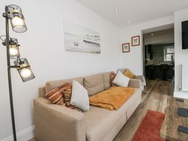 A living room with a sofa, lamp, and wall art at Holy Trinity Cottage in Millom
