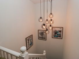 A staircase with hanging lights and framed pictures at Holy Trinity Cottage in Millom