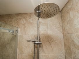 A shower with a large shower head and tile wall at Holy Trinity Cottage in Millom