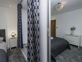 A bedroom featuring a bed, lamp, and dresser at Holy Trinity Cottage in Millom