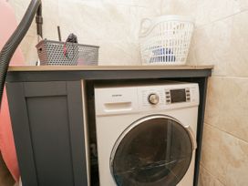 A laundry room with a washing machine and laundry baskets at Holy Trinity Cottage in Millom