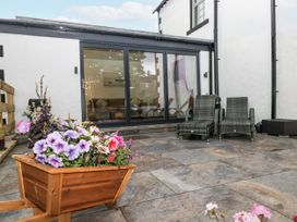 A garden patio with a flower planter and chairs at Holy Trinity Cottage in Millom