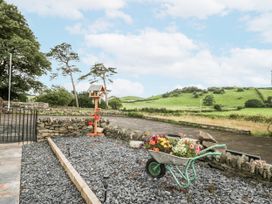 An outdoor area with a wheelbarrow of flowers at Holy Trinity Cottage Millom