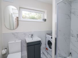 A bathroom with a toilet, sink, washer, and shower at 7 Belfort Court