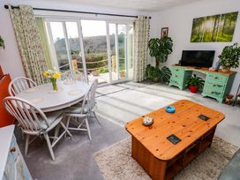 A living room with a table, chairs, and a television at No.51 Llanteg Park in Amroth