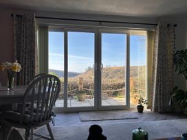A dining room with sliding doors and a view of the outdoor landscape at No.51 Llanteg Park Amroth