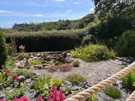 A garden with flowers and a pond at 51 Llanteg Park Amroth