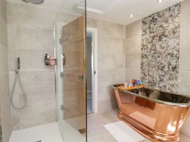A bathroom with a glass shower and a copper bathtub at Barn Howe in Lyth near Levens