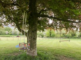 A tree with a swing and play structure in a grassy area at Barn Howe Lyth near Levens