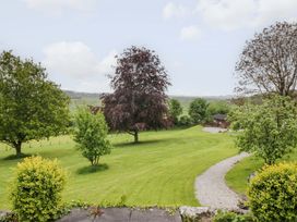 A garden with trees, grass, and a path at Barn Howe in Lyth near Levens